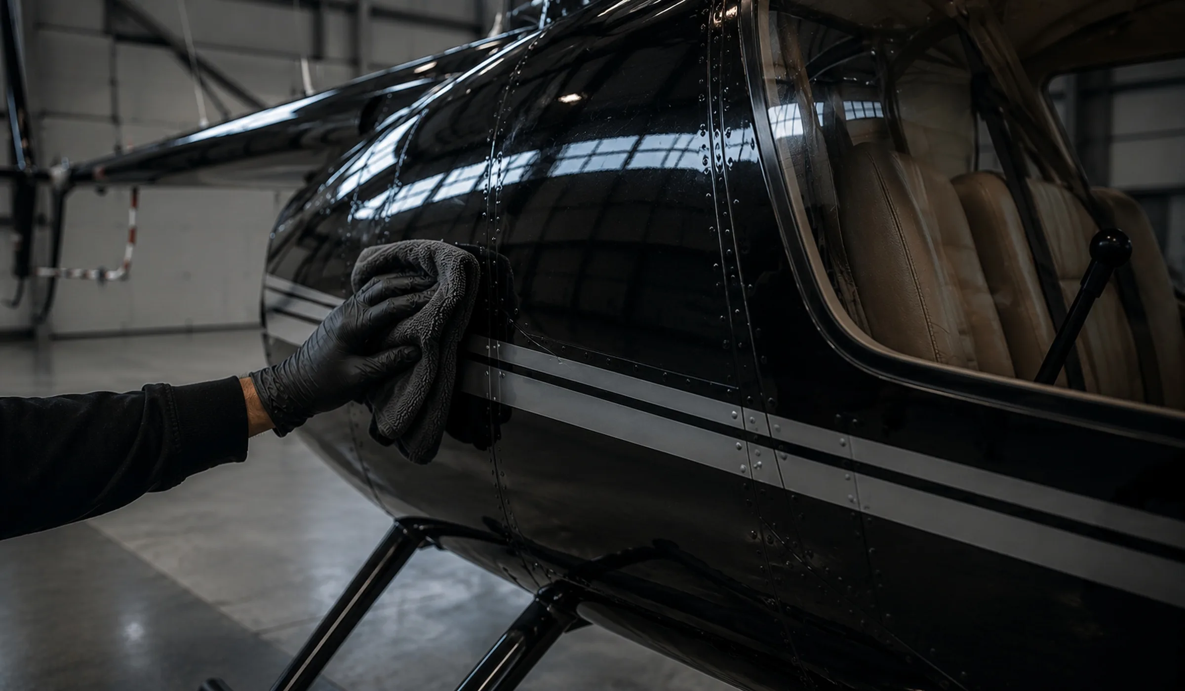 Technician hand-cleaning an aircraft surface in a hangar